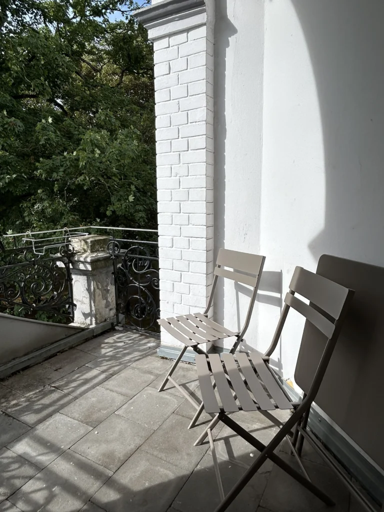 Shiatsu Krefeld mit kleinem Balkon, zwei kleinen grauen St&uuml;hlen und einem zusammengeklappten Tischchen.