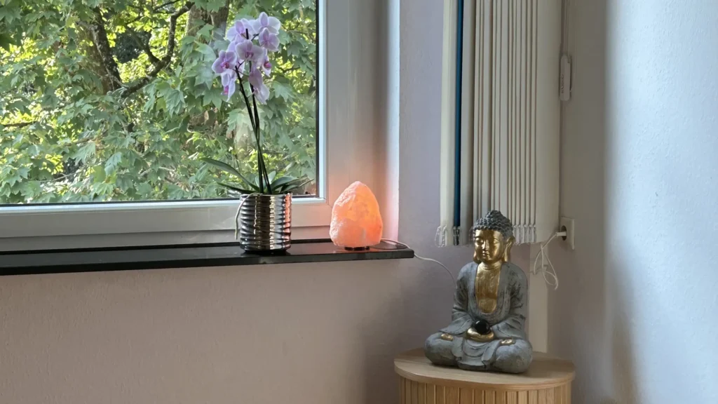 Shiatsu Krefeld, Raumdetail mit Budda, leuchtender Salzlampe und Orchidee am Fenster